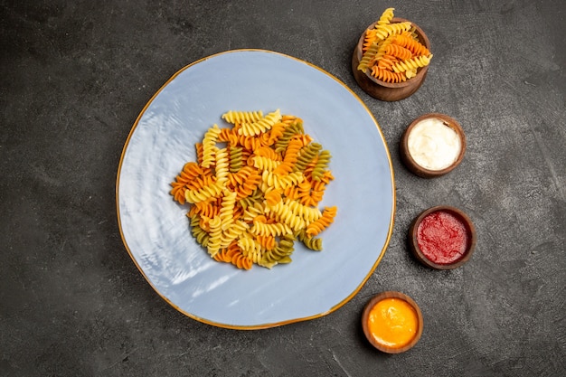 Kostenloses Foto draufsicht leckere italienische pasta ungewöhnliche gekochte spiralnudeln auf grau