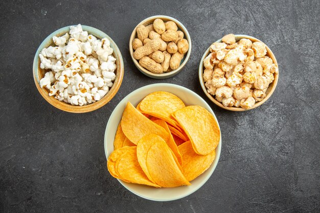 Draufsicht leckere Käsechips mit verschiedenen Snacks auf dem dunklen Hintergrund