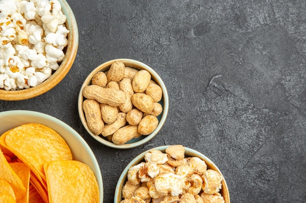 Draufsicht leckere Käsechips mit verschiedenen Snacks auf dem dunklen Hintergrund