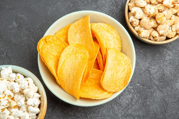 Draufsicht leckere Käsechips mit verschiedenen Snacks auf dem dunklen Hintergrund