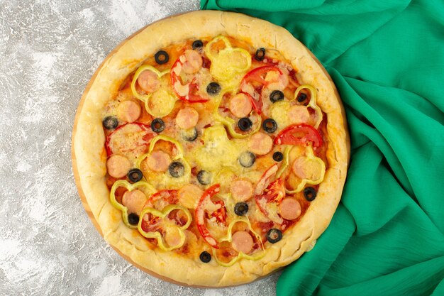 Draufsicht leckere käsige Pizza mit Würstchen der schwarzen Oliven und roten Tomaten auf dem grauen Hintergrund mit grünem Tissue-Fastfood-italienischem Teigmehlauflauf