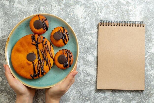 Draufsicht leckere Kakaokuchen mit Schokoladenglasur in der Platte auf hellweißer Oberfläche Kuchen Keks Dessert süßer Kekskuchen