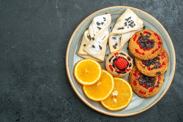 Draufsicht leckere Kekse mit fruchtigem Gebäck und Orangenscheiben auf dunklem Hintergrund Obst süßer Kuchen Kuchen Tee Zucker