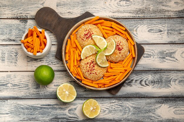 Draufsicht leckere Kekse mit Zitronenscheiben und Zwieback auf dem rustikalen grauen Schreibtisch-Snack-Kekszucker-süßen Kuchenplätzchen