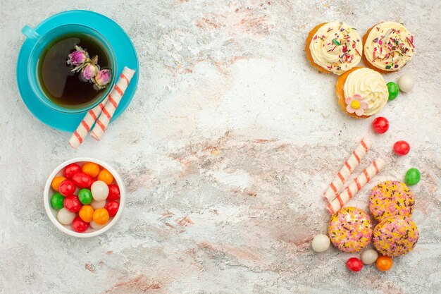 Draufsicht leckere Kekskuchen mit Bonbons und Tasse Tee auf weißer Oberfläche Kuchen Keks Keks Kuchenfarbe