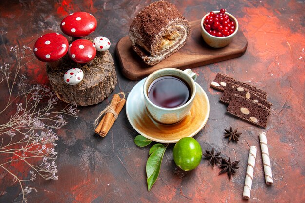 Draufsicht leckere Keksröllchen mit Tasse Tee auf dunklem Schreibtisch