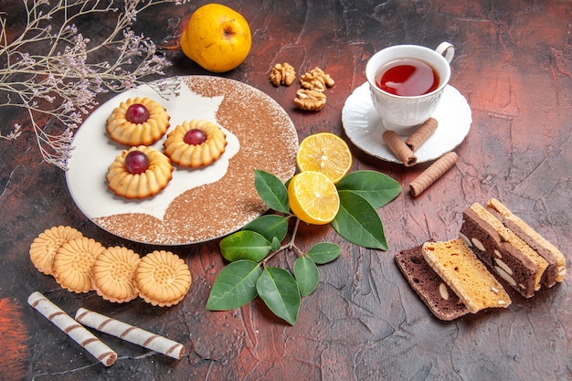 Draufsicht leckere kleine Kekse mit Tasse Tee auf dem dunklen Tischzuckerkuchen süßer Keks