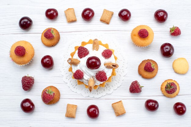 Draufsicht leckere kleine Kuchen mit Himbeeren und Sahne zusammen mit Keksen und Kuchen auf dem leichten Tischkuchen Keks süße Beeren backen Obst