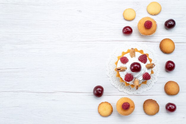 Draufsicht leckere kleine Kuchen mit Himbeeren zusammen mit Keksen und Kuchen auf dem hellen Hintergrundkuchenkeks süße Beere backen Frucht