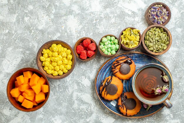 Draufsicht leckere kleine Kuchen mit Tasse Tee und Bonbons auf weißer Oberfläche Kuchen Keks Keks Dessert süßer Tee