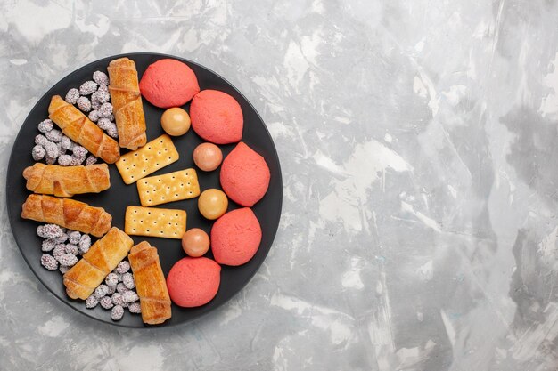 Draufsicht leckere Kuchen mit Bagels und Bonbons auf der hellweißen Oberfläche