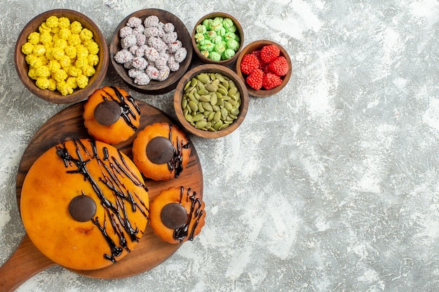 Draufsicht leckere Kuchen mit Schokoladenglasur und Bonbons auf weißem Schreibtischkuchen Kakao-Keks-Kuchen-Dessert süßer Keks