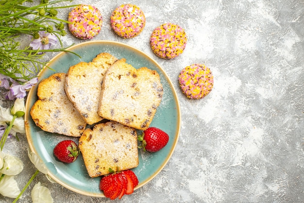 Draufsicht leckere Kuchenscheiben mit Erdbeeren und Keksen auf Licht