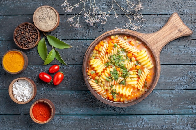 Draufsicht leckere nudelsuppe aus spiralförmiger italienischer pasta mit gewürzen auf dunkelblauem schreibtisch nudelsuppe farbgericht abendessen küche