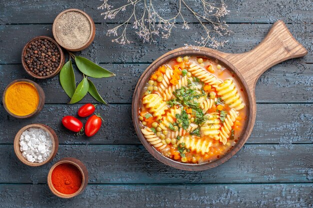 Draufsicht leckere Nudelsuppe aus spiralförmiger italienischer Pasta mit Gewürzen auf dunkelblauem Schreibtisch Nudelsuppe Farbgericht Abendessen Küche