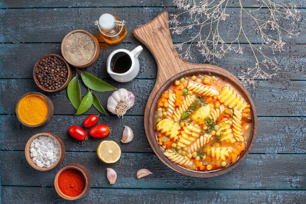 Draufsicht leckere Nudelsuppe aus spiralförmiger italienischer Pasta mit Gewürzen auf dunkelblauer Schreibtischküche Nudelsuppe Farbgericht Abendessen