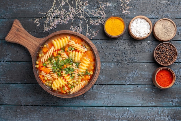 Kostenloses Foto draufsicht leckere nudelsuppe aus spiralförmiger italienischer pasta mit verschiedenen gewürzen auf dunkler schreibtischsuppe farbe italienische pastagericht küche