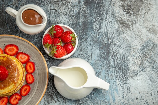 Draufsicht leckere Pfannkuchen mit Erdbeeren und Honig auf dem Licht