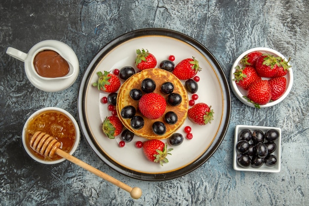 Draufsicht leckere Pfannkuchen mit frischen Früchten und Honig auf Licht