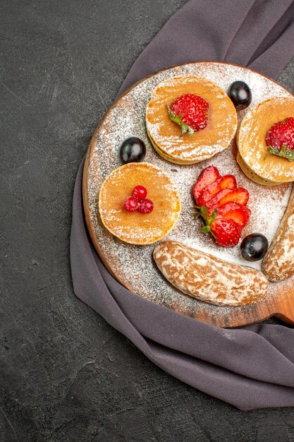 Draufsicht leckere Pfannkuchen mit Früchten und süßen Kuchen auf dunklem Boden