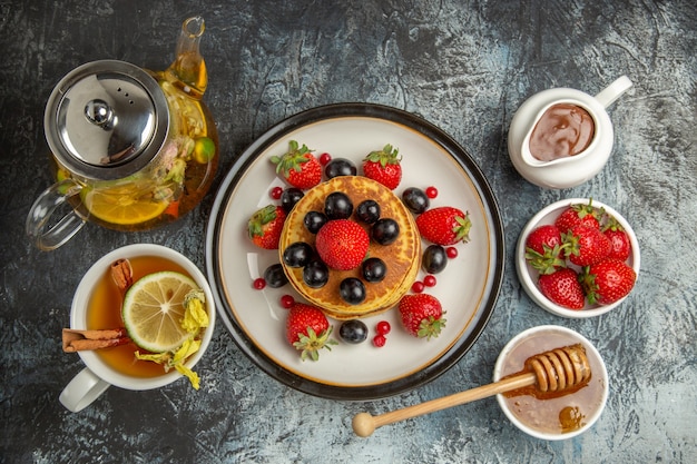 Draufsicht leckere Pfannkuchen mit Früchten und Tee auf hellem Boden süßes Obstfrühstück