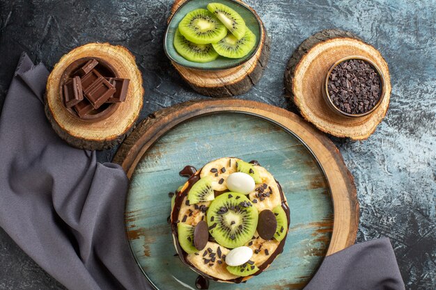 Draufsicht leckere Pfannkuchen mit geschnittenen Früchten und Schokolade auf dunkelgrauer Oberfläche süße Farbe Frühstück Zuckerkuchen Dessert