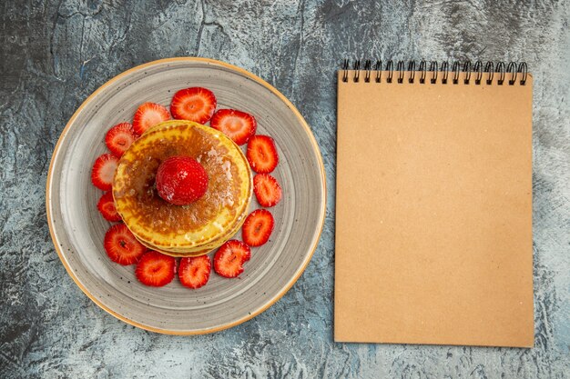 Draufsicht leckere Pfannkuchen mit Honig und Erdbeeren auf Licht