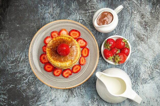 Draufsicht leckere Pfannkuchen mit Honig und Erdbeeren auf Licht