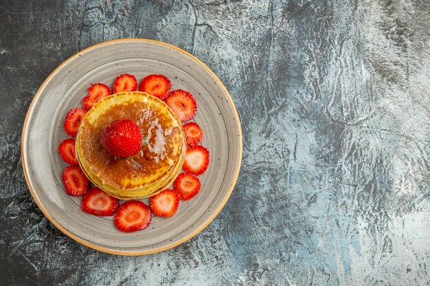 Draufsicht leckere Pfannkuchen mit Honig und Erdbeeren auf Licht