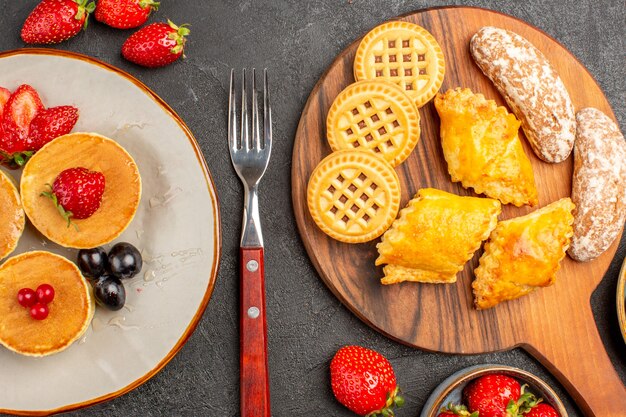 Draufsicht leckere Pfannkuchen mit Obst und Kuchen im Dunkeln