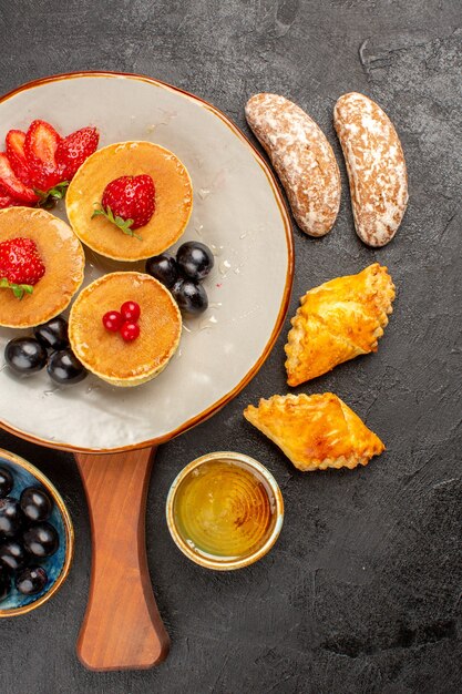 Draufsicht leckere Pfannkuchen mit Obst und Kuchen im Dunkeln