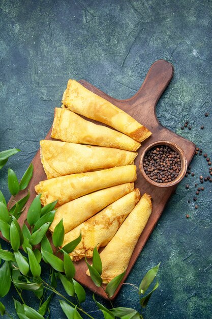 Draufsicht leckere Pfannkuchen mit Pfeffer auf dunklem Hintergrund gerollt Kuchen Fleisch Gebäck Hotcake Teig süße Kuchenmahlzeit Farbe