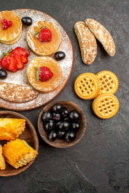 Draufsicht leckere Pfannkuchen mit verschiedenen Süßigkeiten auf dem dunklen Oberflächenzuckerkuchen-Dessert