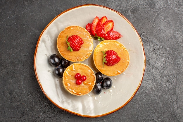 Kostenloses Foto draufsicht leckere pfannkuchen wenig geformt mit früchten im dunkeln
