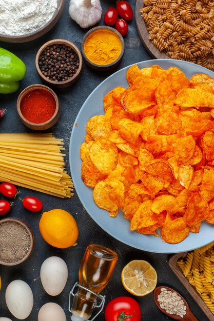 Draufsicht leckere Pfefferchips mit verschiedenen Gewürzen und Zutaten auf dunklem Hintergrund Essen Mahlzeit Foto Pasta