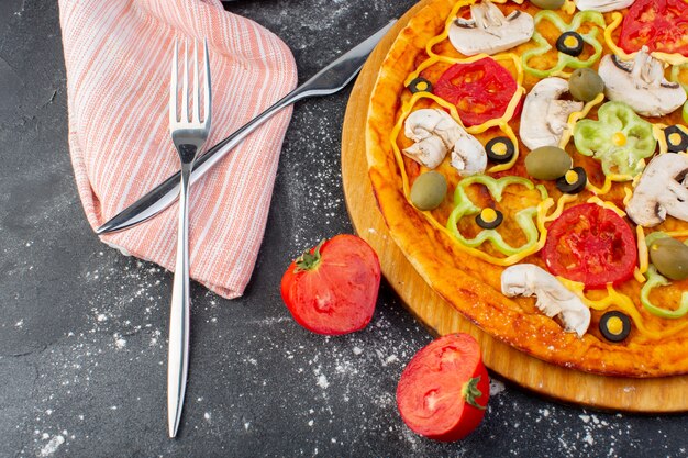 Draufsicht leckere Pilzpizza mit roten Tomaten grüne Oliven Pilze mit frischen Tomaten überall auf dem dunklen Schreibtisch Pizzateig italienisches Essen