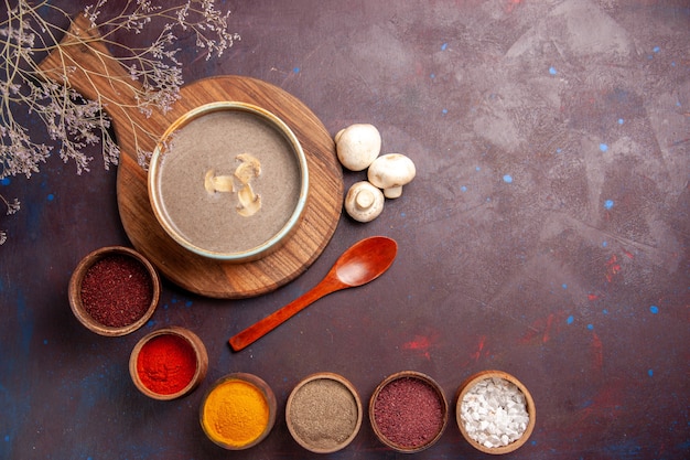 Draufsicht leckere Pilzsuppe mit verschiedenen Gewürzen auf dunklem Hintergrund Suppenmahlzeit Pilzgewürznahrung