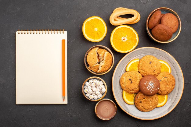 Draufsicht leckere Sandkekse mit geschnittenen Orangen auf dem dunklen Hintergrund Obst Zitrus Keks süßer Kuchen Keks