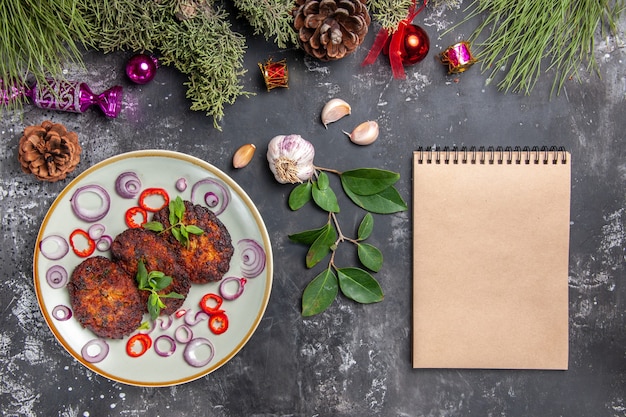 Draufsicht leckere Schnitzel mit Zwiebelringen auf grauem Schreibtischmahlzeitfotoschalenfleisch