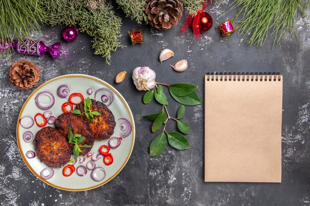 Draufsicht leckere Schnitzel mit Zwiebelringen auf grauem Schreibtischmahlzeitfotoschalenfleisch