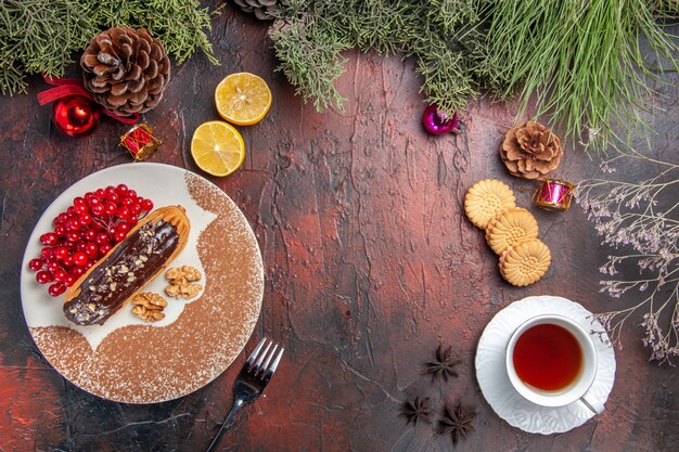 Draufsicht leckere Schoko-Eclairs mit Beeren und Tee auf dunklem Tisch süßer Kuchenkuchen-Nachtisch