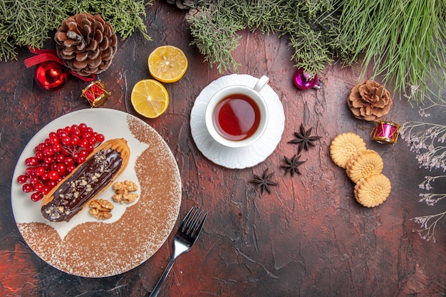 Draufsicht leckere Schoko-Eclairs mit Beeren und Tee auf dunklem Tischkuchenkuchen-Nachtisch süß