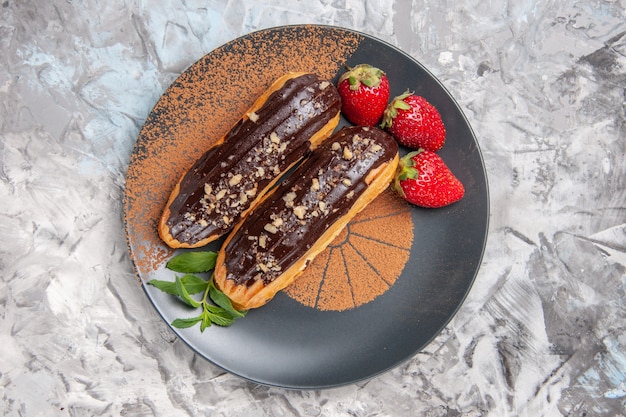 Draufsicht leckere Schoko-Eclairs mit Erdbeeren auf dem leichten Dessertkeksplätzchen