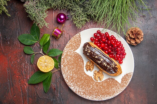 Draufsicht leckere Schoko-Eclairs mit roten Beeren auf dunklem Tischkuchen-Kuchen-Nachtisch süß
