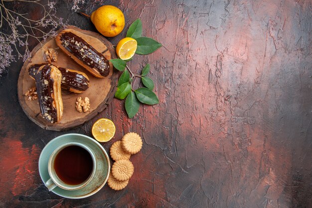 Draufsicht leckere Schoko-Eclairs mit Tasse Tee auf dem süßen Tischdessert süßer Kuchen