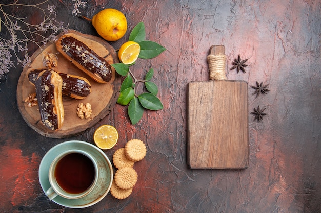 Draufsicht leckere Schoko-Eclairs mit Tasse Tee auf dem süßen Tischdessert süßer Kuchen