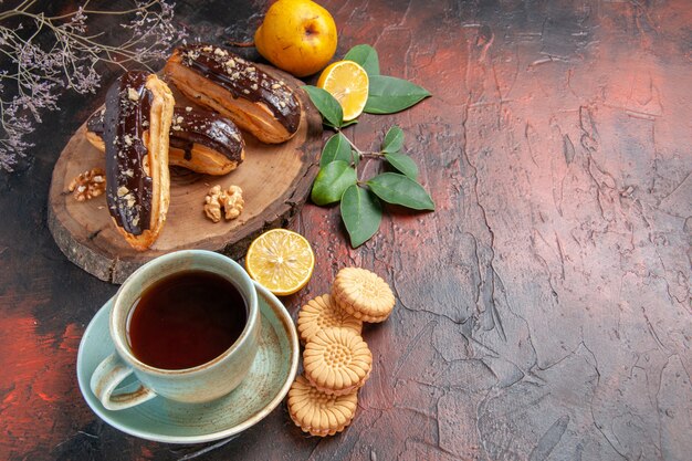 Draufsicht leckere Schoko-Eclairs mit Tasse Tee auf dem süßen Tischdessert süßer Kuchen