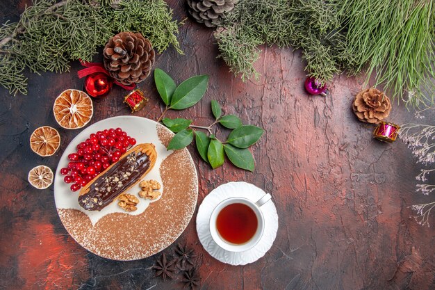 Draufsicht leckere Schoko-Eclairs mit Tee und Beeren auf dem dunklen Tisch süßer Kuchen-Kuchen-Nachtisch