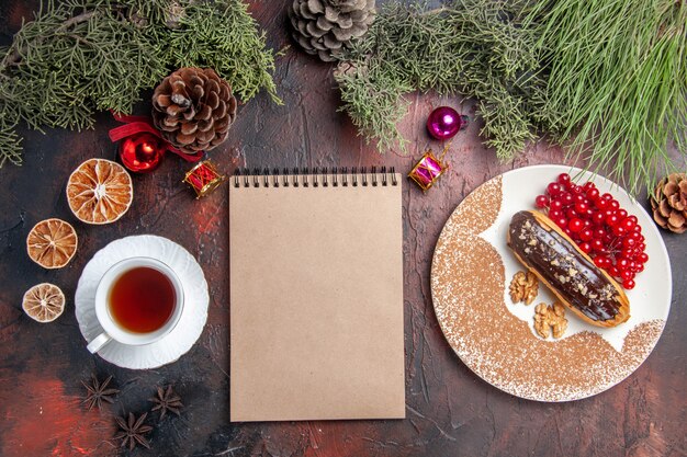 Draufsicht leckere Schoko-Eclairs mit Tee und Beeren auf dunklem Bodenkuchen süßer Dessertkuchen