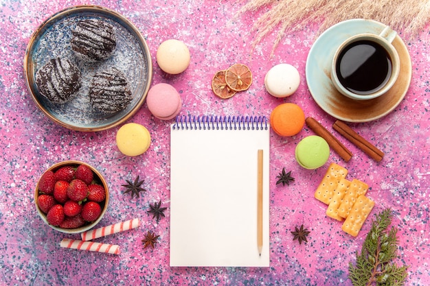 Draufsicht leckere Schokoladenkuchen mit französischen Macarons auf dem Rosa